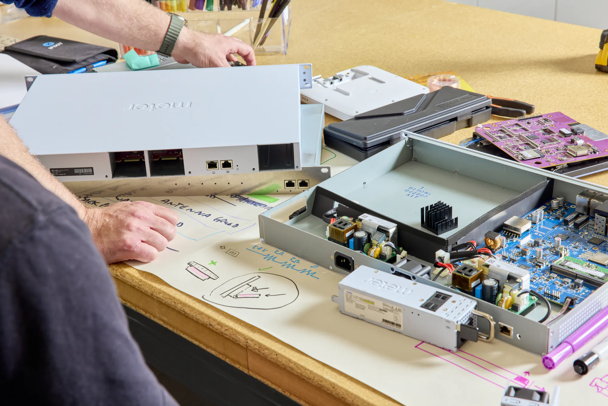 Opened Meter switch, firewall, and access point chassis on a workbench with sketches of installation processes